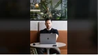 Vertical front view of a creator with a laptop at a cafe table